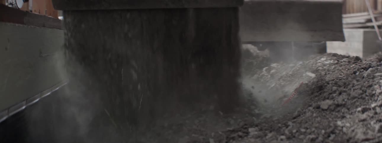 A man operates a construction vehicle and dumps rocks into a pile