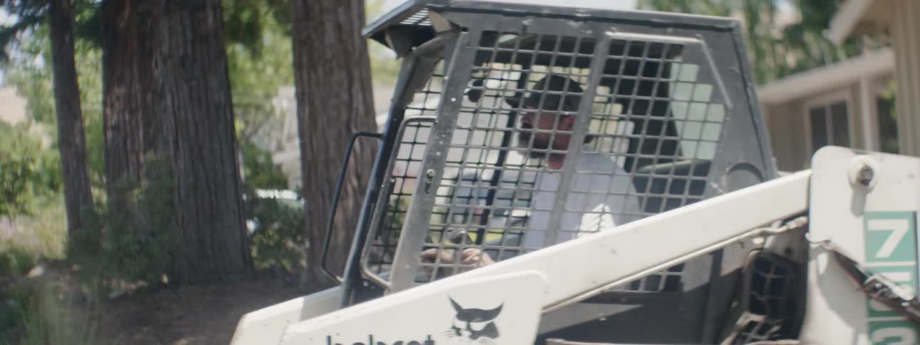 A man operating a construction vehicle in a neighborhood