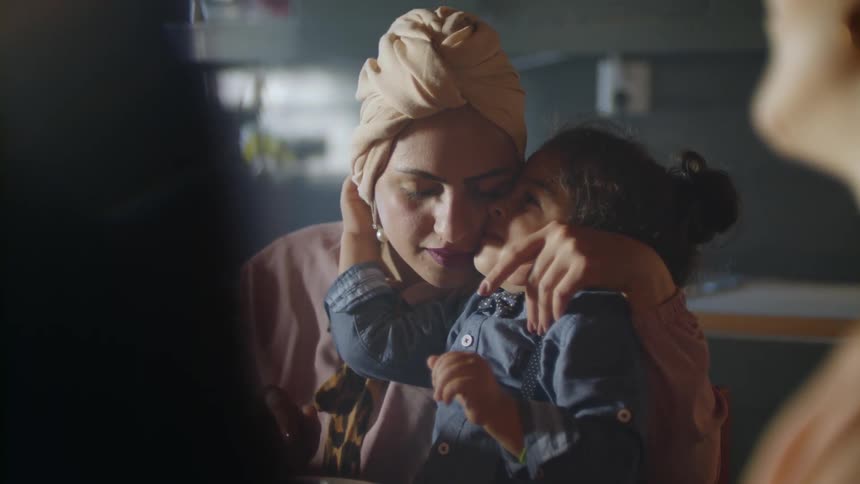 A toddler hugs her Mother at the dinner table