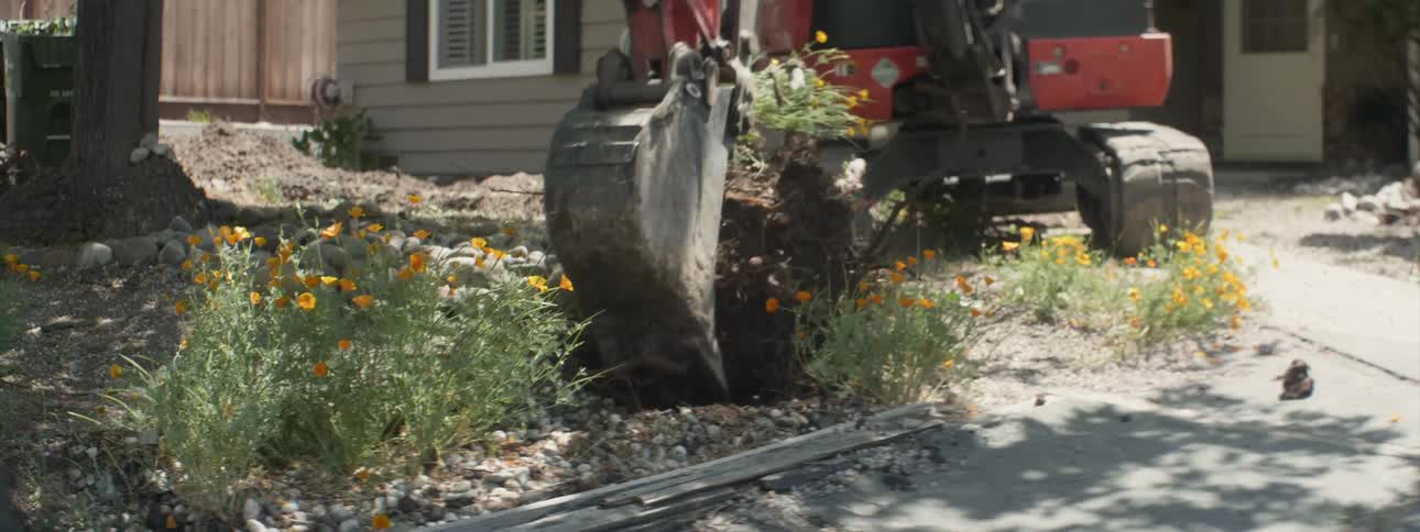 The construction machine digs up the flower bed