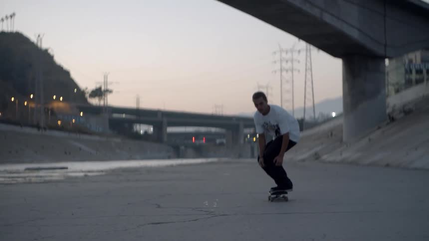 A man skateboards beneath city bridges