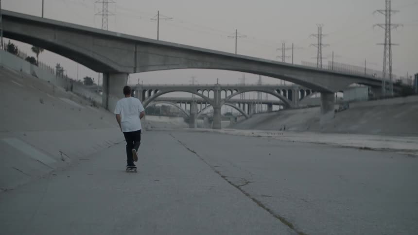 Man riding a skateboard in channels with an overcast sky