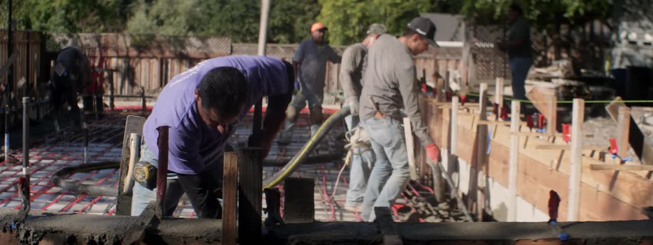 Men work at a construction site in a backyard