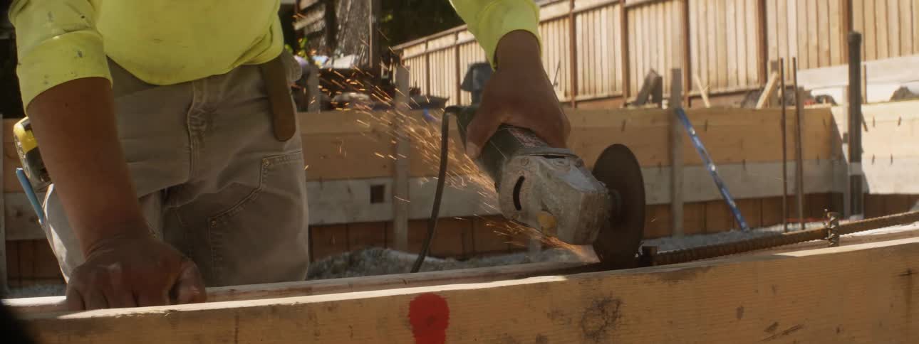A worker uses a powertool at a construction site