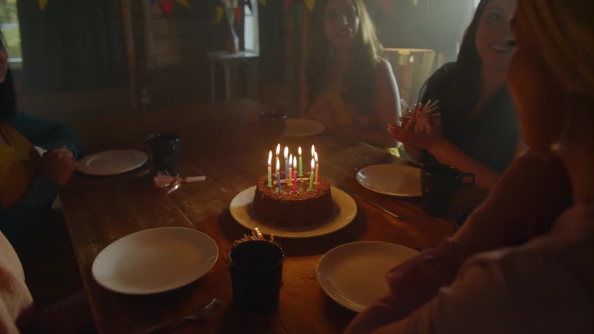 A woman blows out candles on a birthday cake