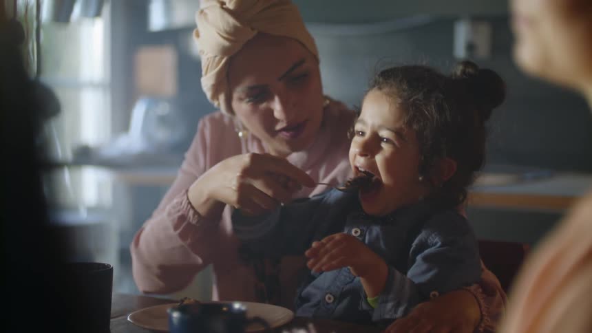 A woman is holding a child at the table