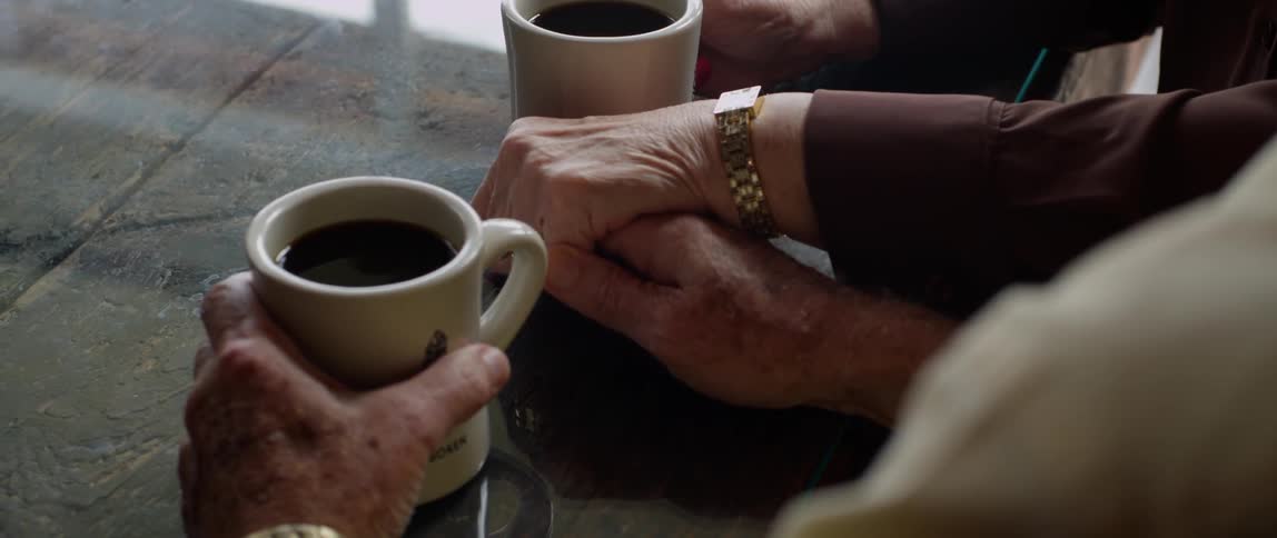 Two people holding hands as they sit down for a drink
