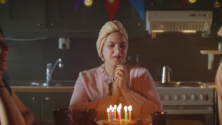 A birthday cake is placed in front of a smiling woman