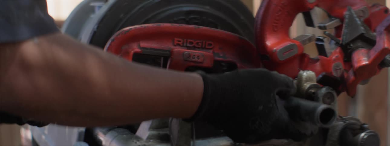 A man wearing gloves adjusts equipment on a construction site