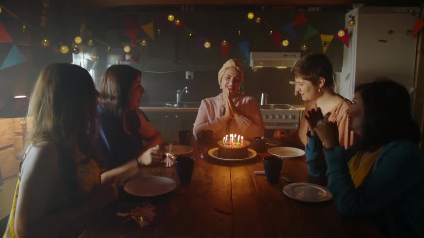 Woman puts a birthday cake on the table surrounded by women