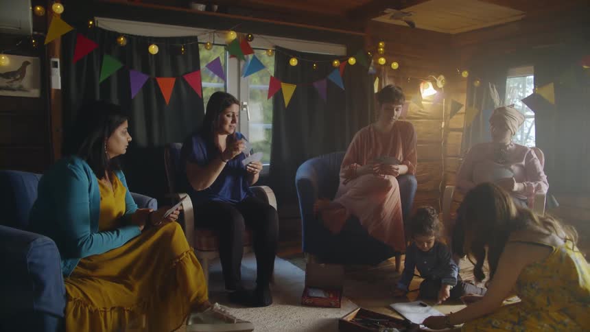 A group of women sit together playing cards