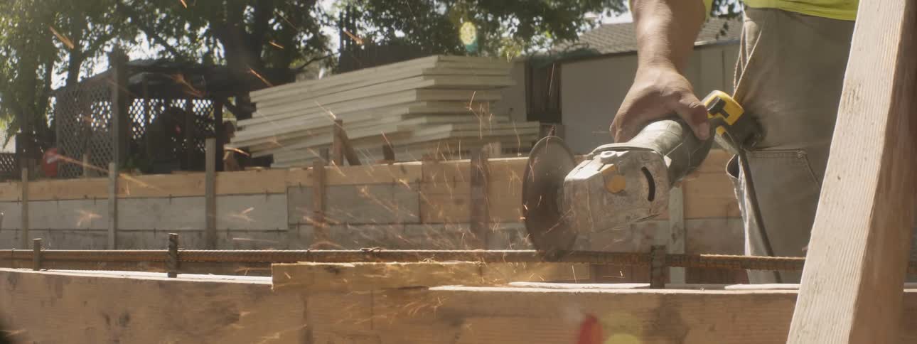 A man at a construction site uses an electric saw to cut wood