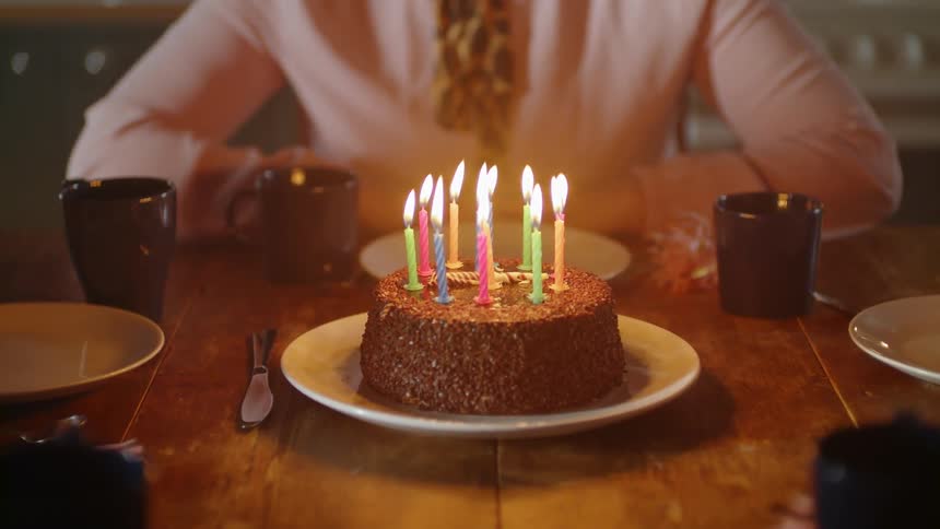 A woman blows out candles on a birthday cake