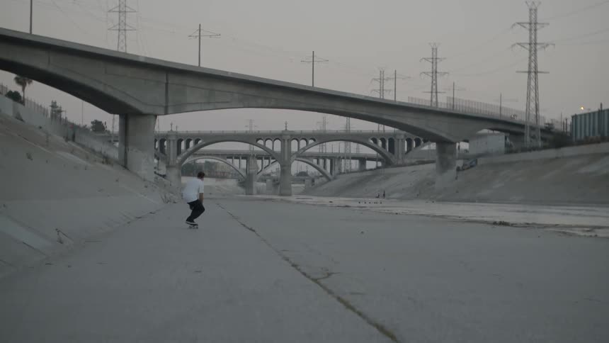 A man skateboards beneath city bridges