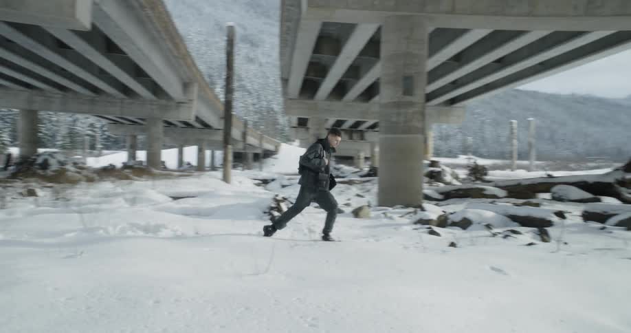 A man walks in snow beneath an overpass