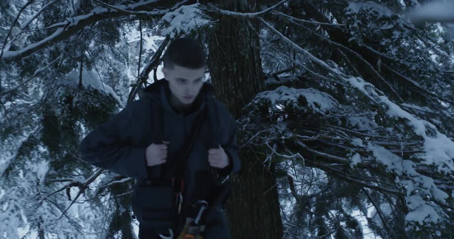 A man carrying a backpack walks through a snow covered area with trees