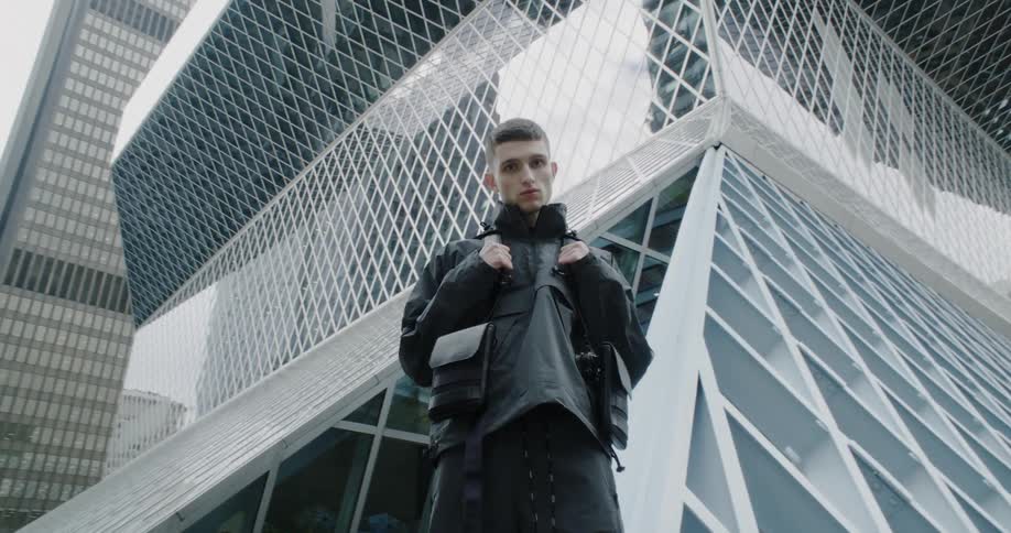 A man poses in front of a tall city building