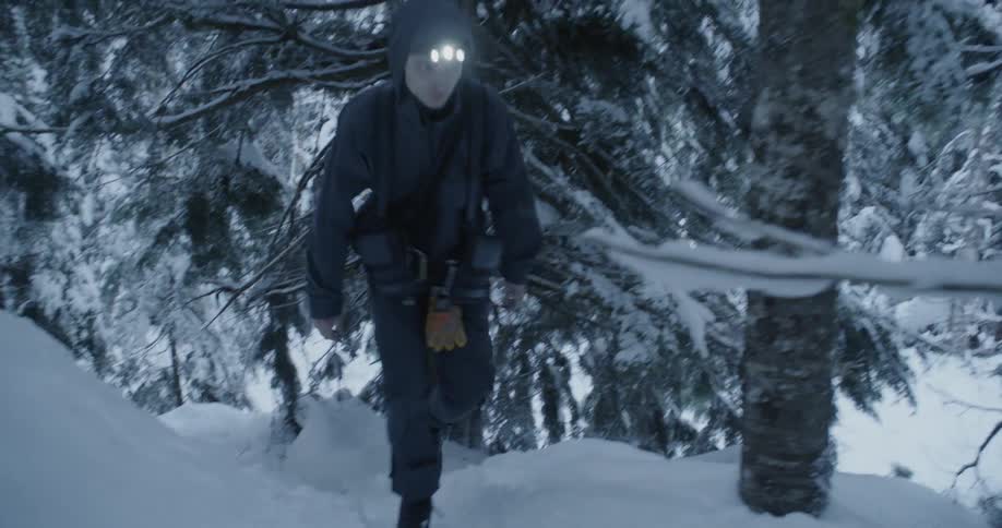 A man hikes uphill in the snow of the forest