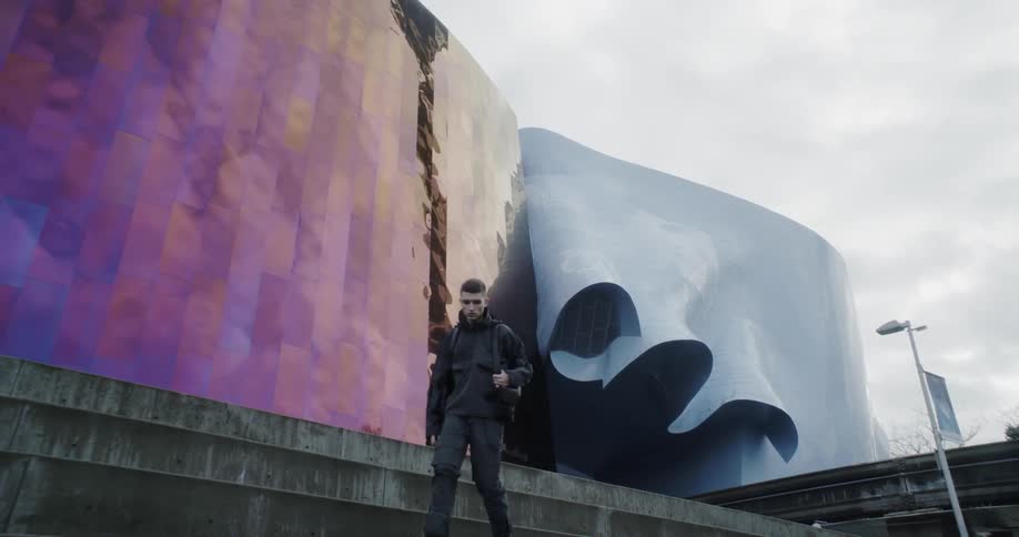 A man walks down the steps in front of a large building