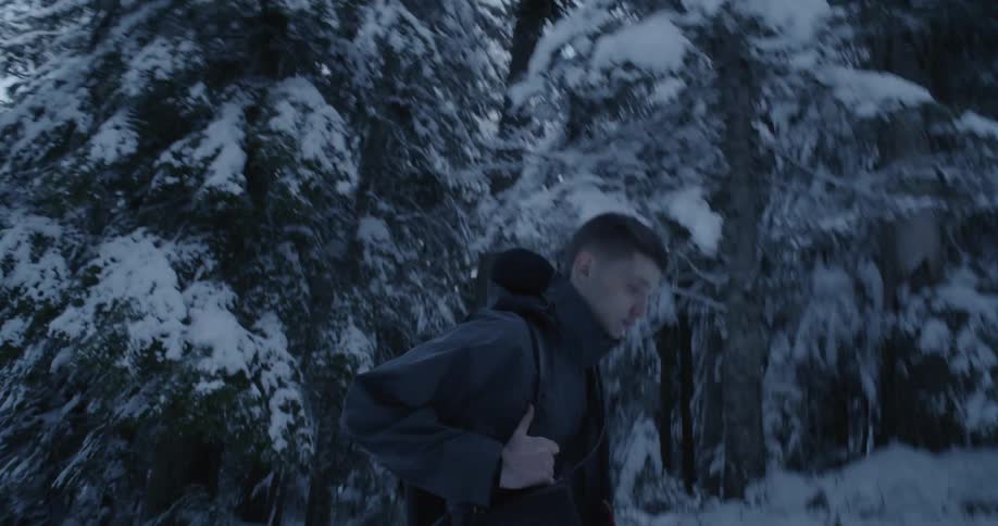 A man hikes in a snowy forest