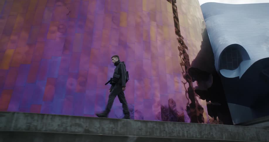 Man walks outside a large building with a reflective wall