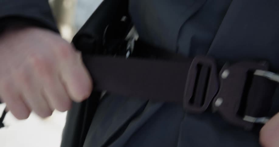A man tightens a utility belt around his waist