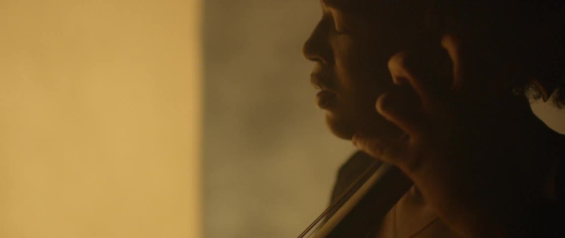 Fog flows around a cellist in the dark