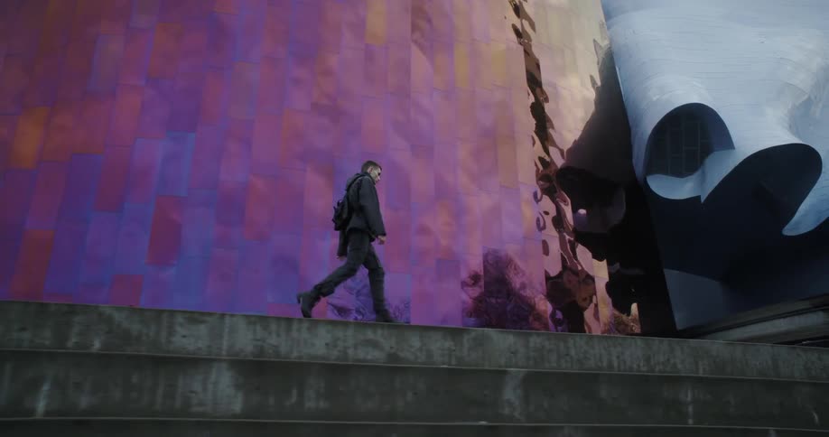 The man walks past the reflective building