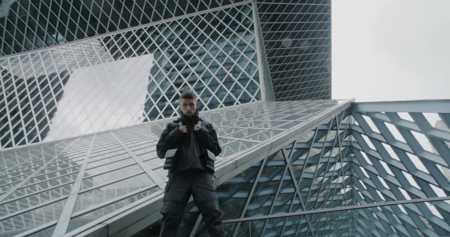 A man standing in front of a large building with many windows and posing