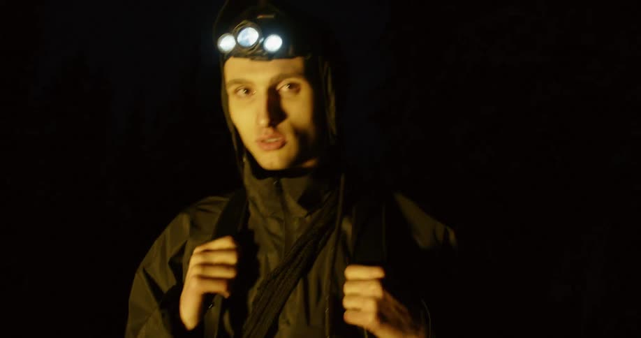 A man wears a headlamp while hiking in the dark
