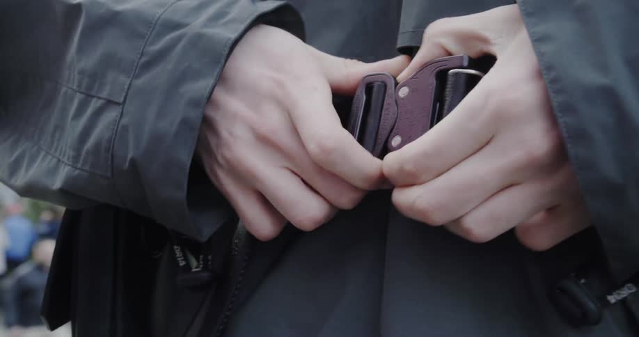 Man undoes the buckle of his belt
