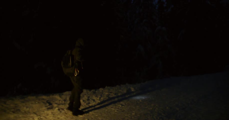 A man hikes in a snowy forest at night