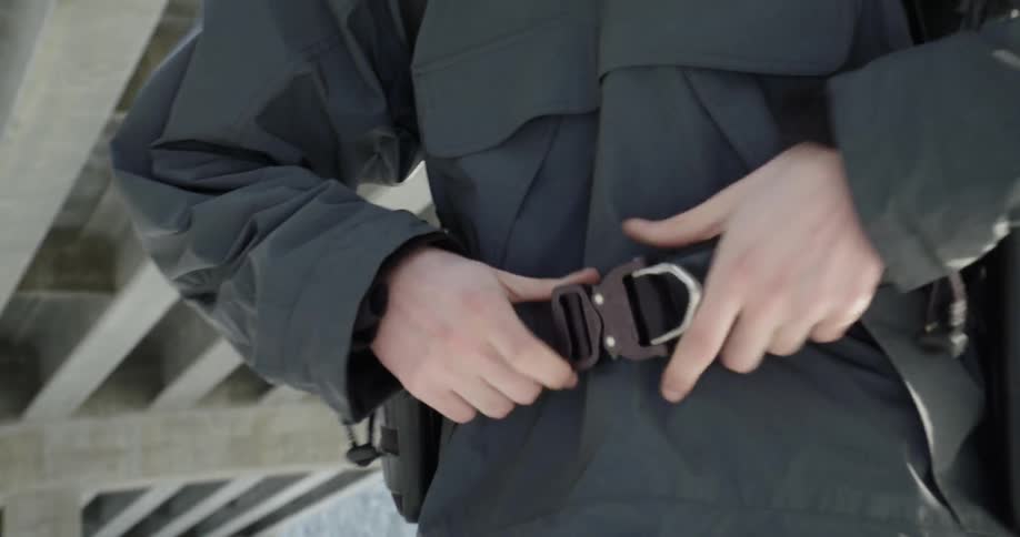 Man puts on a belt and connects the buckle