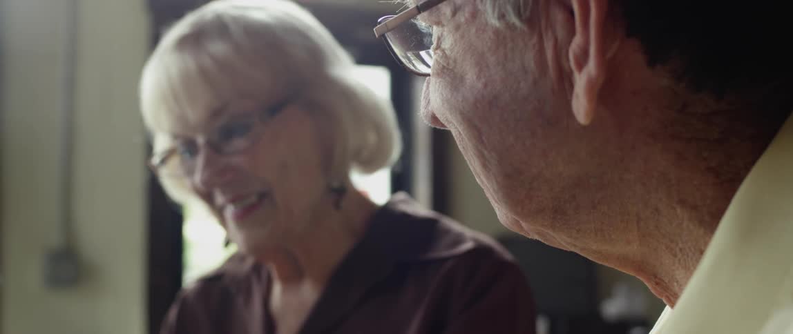 An elderly couple sitting at a public table enjoying each other's company