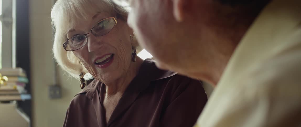 A man and woman wearing glasses talk together