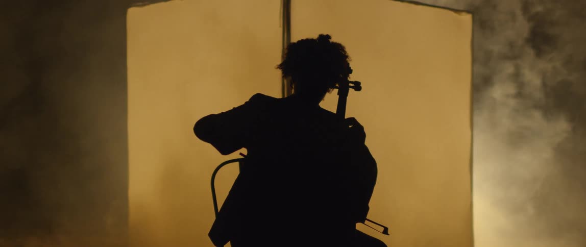The person is sitting in the dark playing an instrument