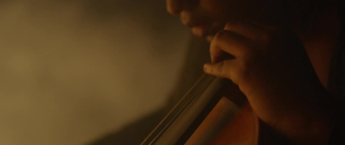 A woman plays the cello at night