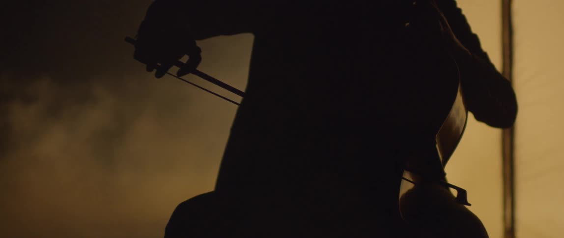 Fog floats around a cellist playing in the dark