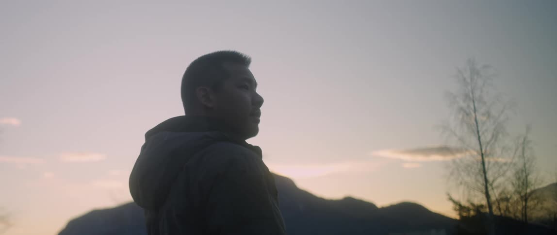 A man stands outside in mountains at sunset