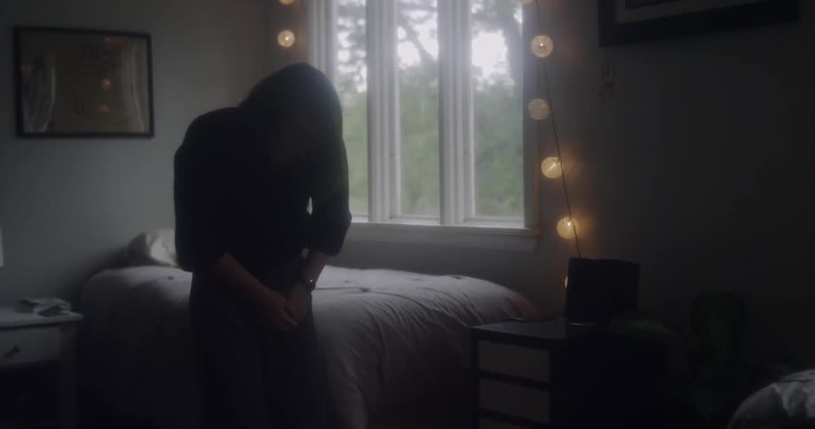 Woman stretches while standing in a bedroom