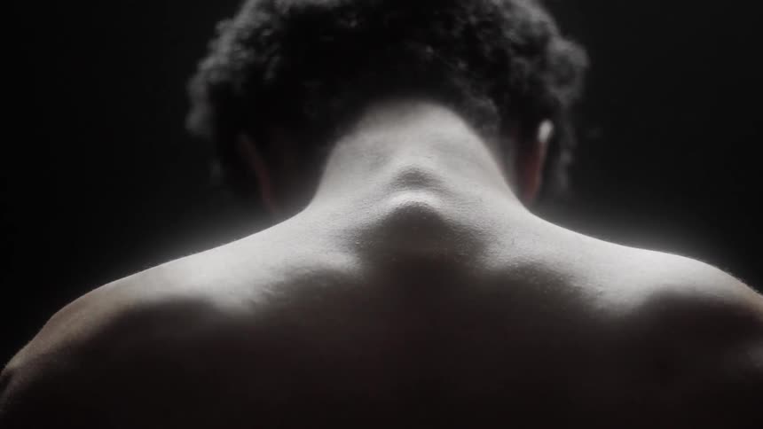 A shirtless man rolls his neck