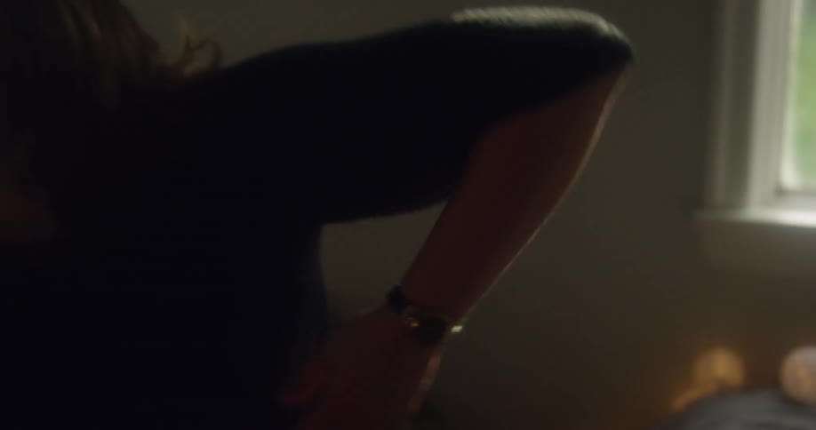 The woman reaches out in the bedroom