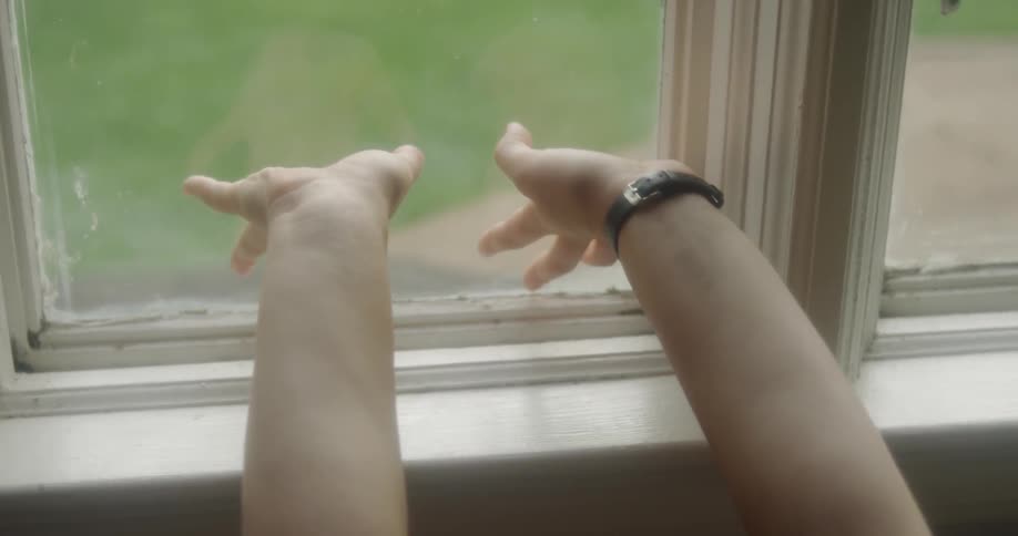 Person stretches their arms against a window pane
