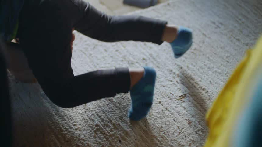 A child plays on the floor with an adult in a bright room