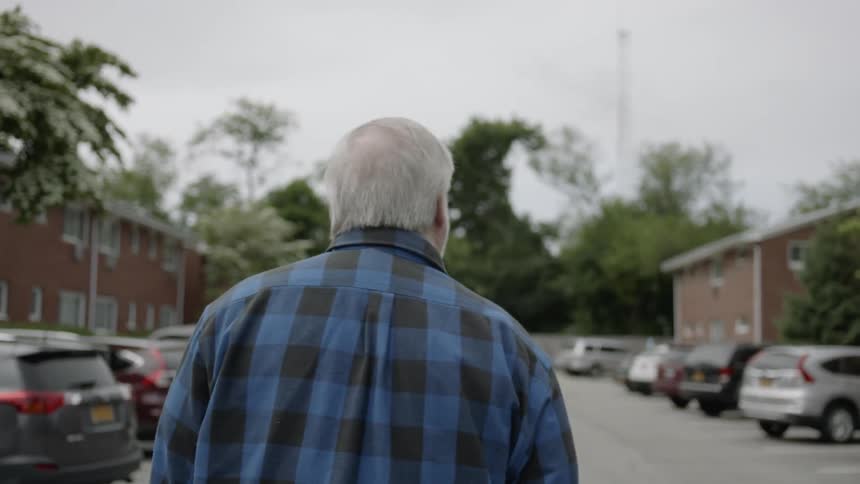 Elderly man walks in a parking lot