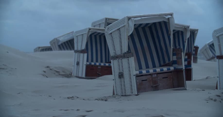 Several wicker pieces of furniture placed randomly on the beach