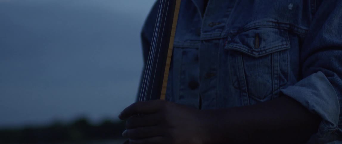 The person is holding a double bass at dawn