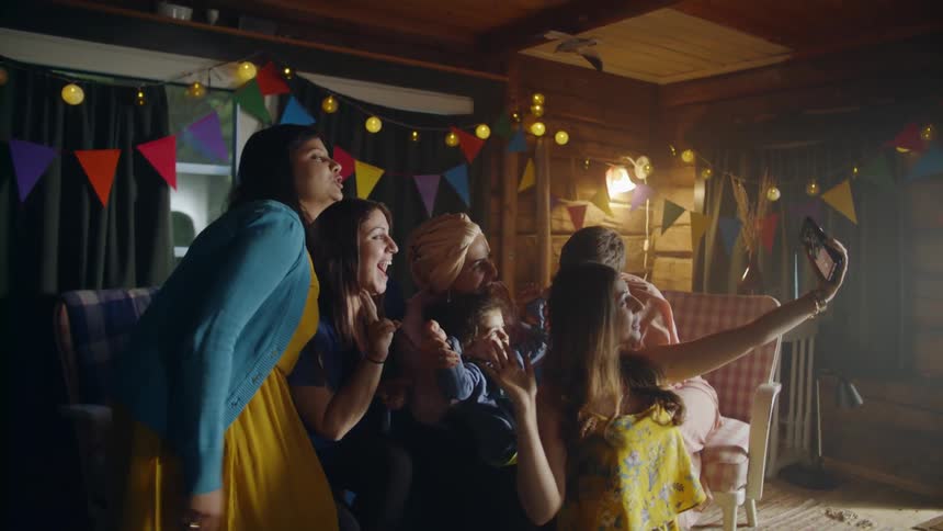 A group of smiling women stand and pose for a photo during a party inside at night