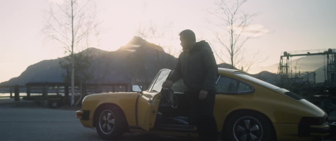 A man gets out of a small yellow vehicle
