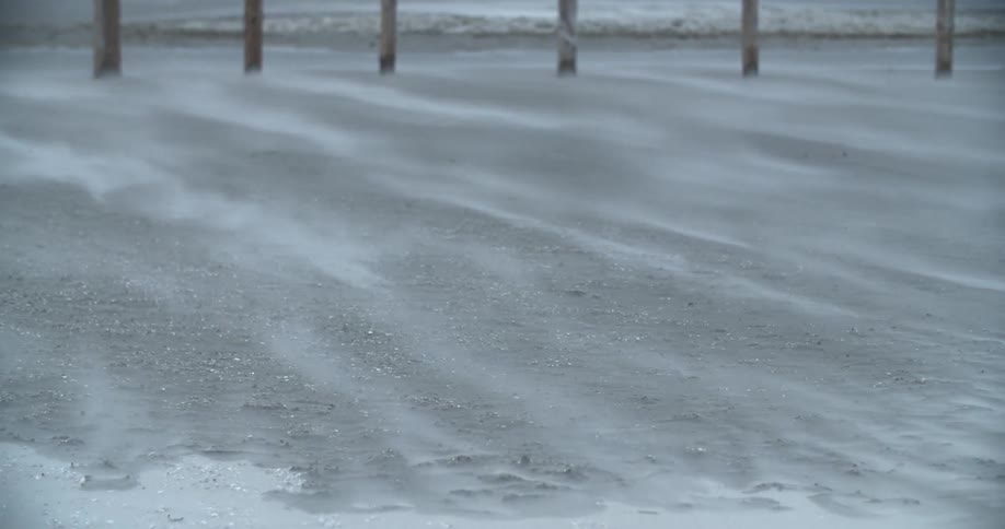 Snow sifts across sandy beach